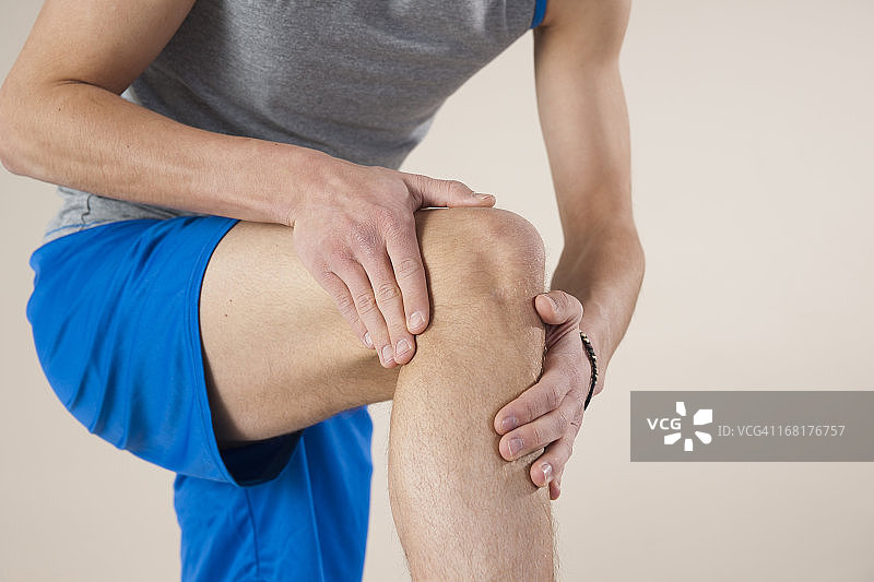 摸膝盖的年轻男人图片素材