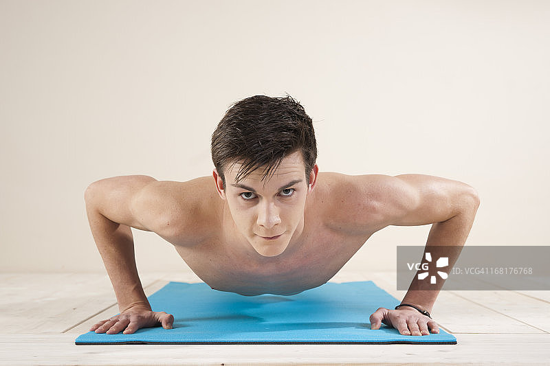 年轻男人在体操垫上做俯卧撑图片素材