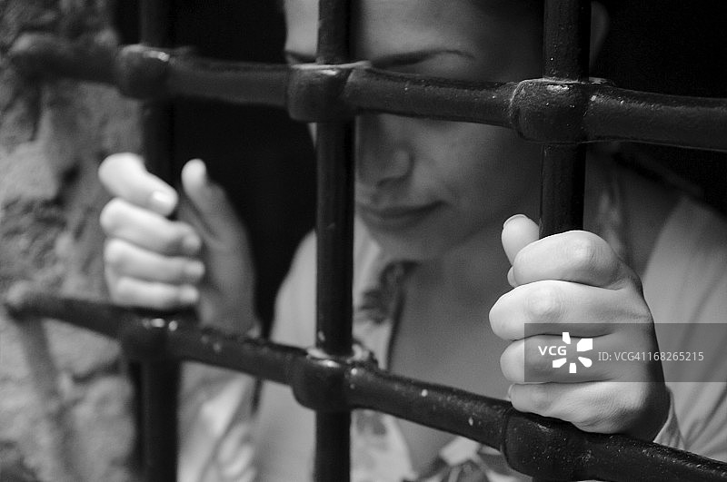 铁栅栏后的年轻女人图片素材