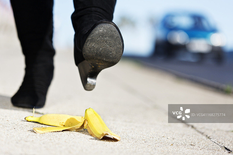 女人的脚靠近香蕉皮；即将发生痛苦的事故图片素材