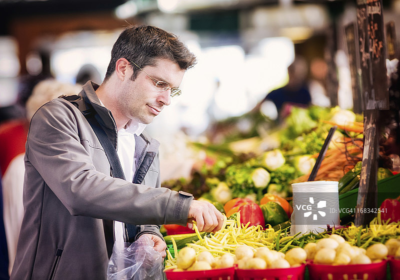 在市场上采摘豆角的英俊单身男人图片素材