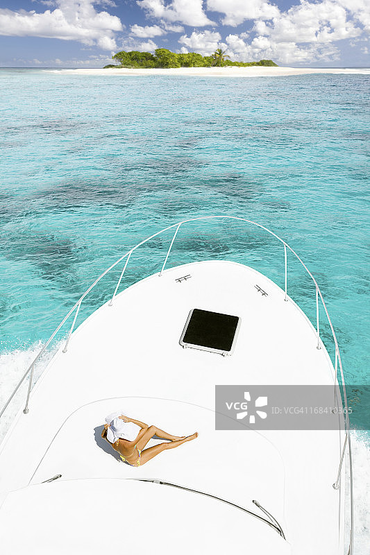 在豪华游艇上享受日光浴，驶向荒岛的女人图片素材