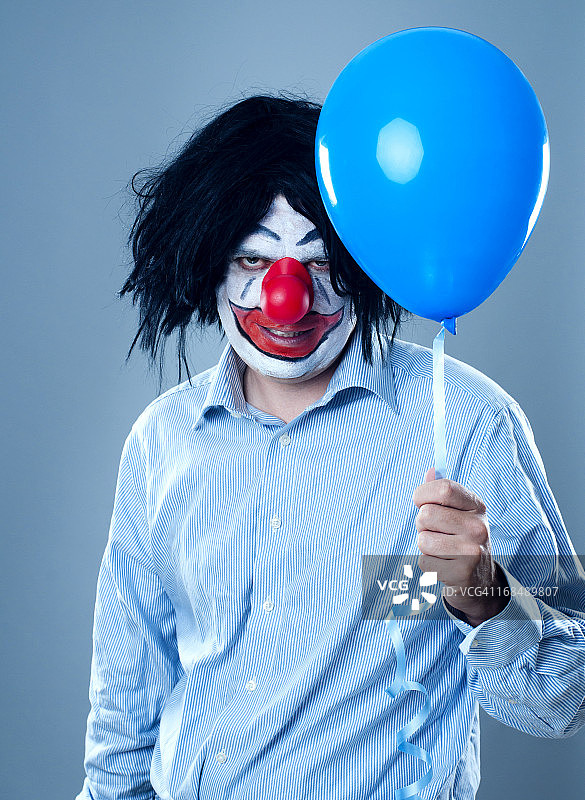 手持蓝色气球的恐怖小丑画像图片素材
