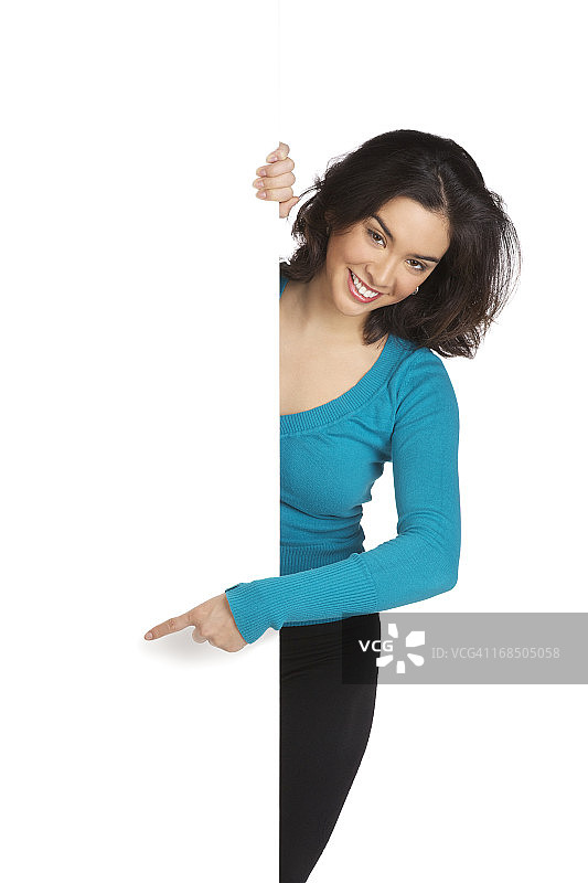 年轻女人指着空白墙壁的孤立图像图片素材