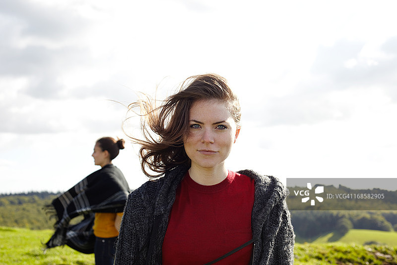 年轻女子看着镜头，微风吹拂着她的头发图片素材