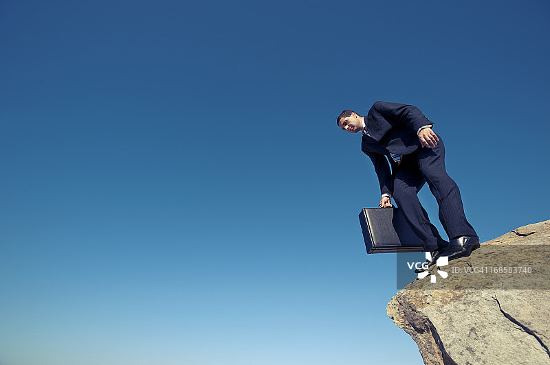 从悬崖边向下看的商人图片素材