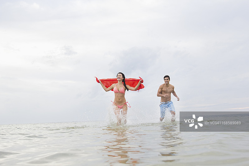 情侣在海滩跑步和玩耍图片素材