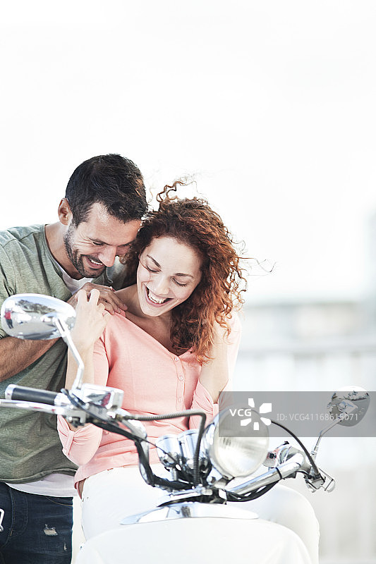 在巴塞罗那骑摩托车和自行车的年轻西班牙夫妇图片素材