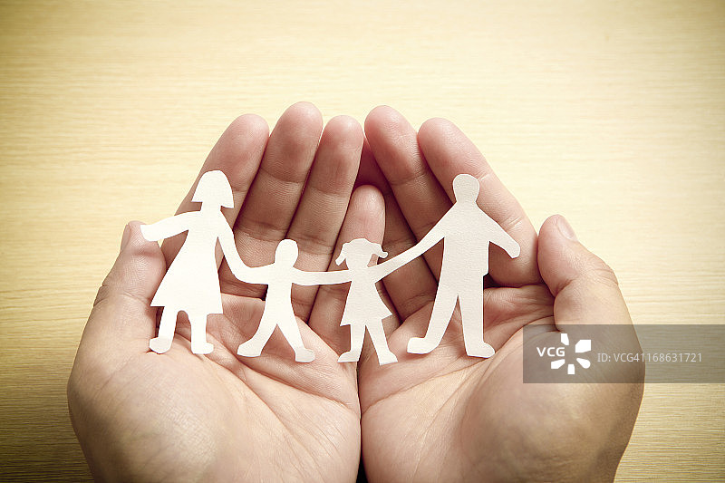 手中的纸质家庭与木纹背景图片素材