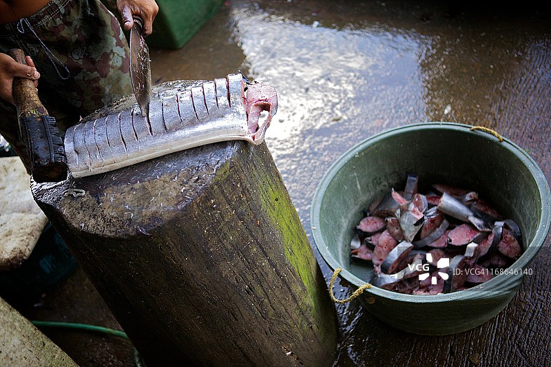 男人将鱼切碎放入篮子图片素材