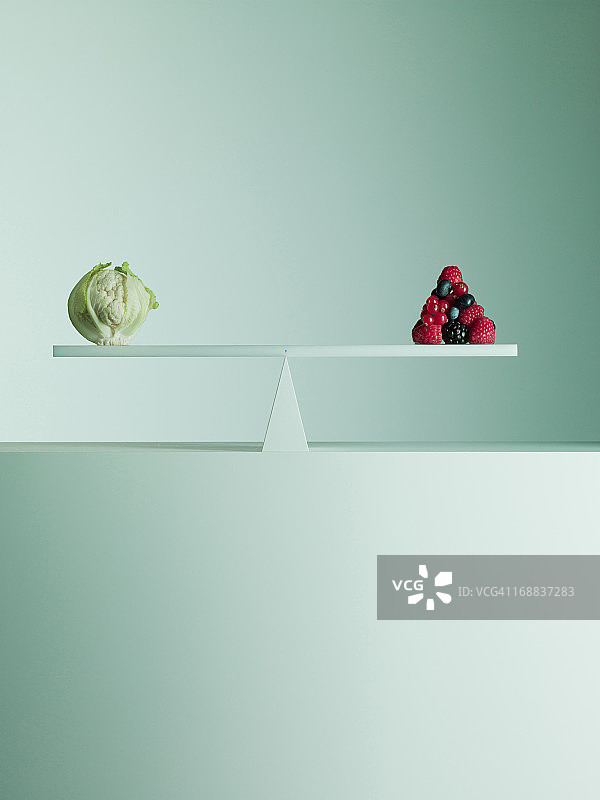 菜花和浆果在跷跷板两端保持平衡图片素材