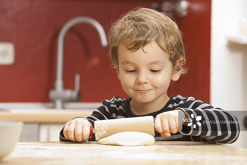 男孩在厨房里擀面图片素材