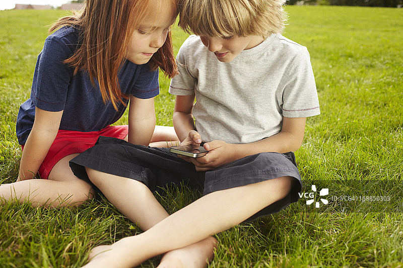 孩子们在草地上使用手机图片素材
