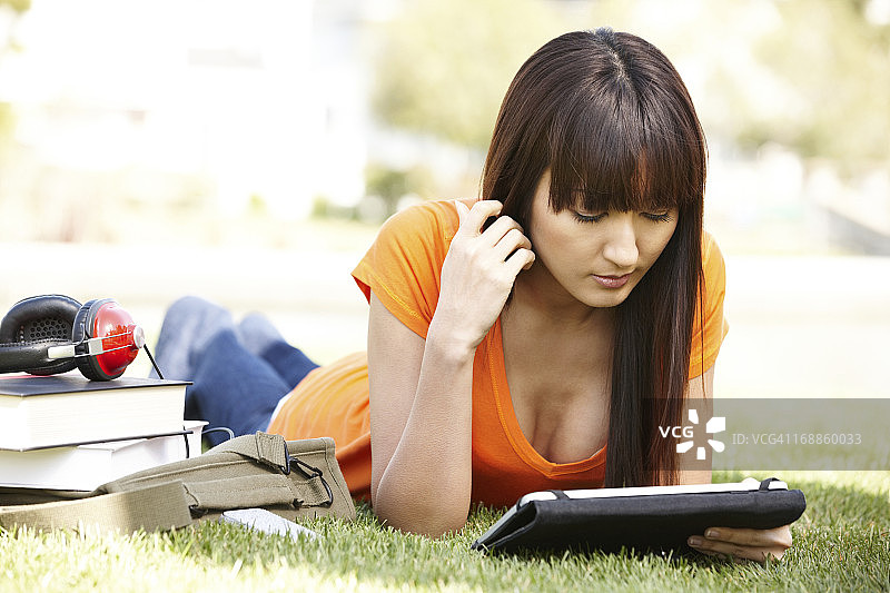 在草地上用平板电脑学习的日本大学生图片素材
