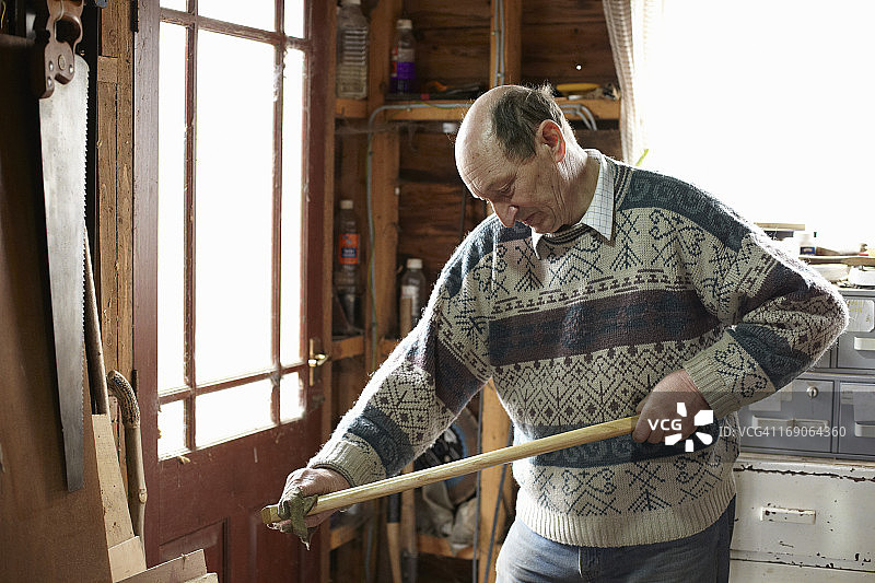 木匠在车间里给扁斧手柄上油图片素材