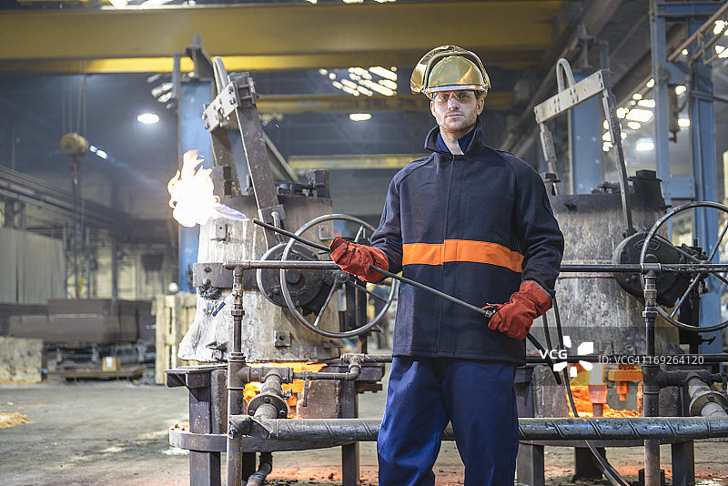 铸造厂工人肖像：戴着面罩，手持火焰枪图片素材