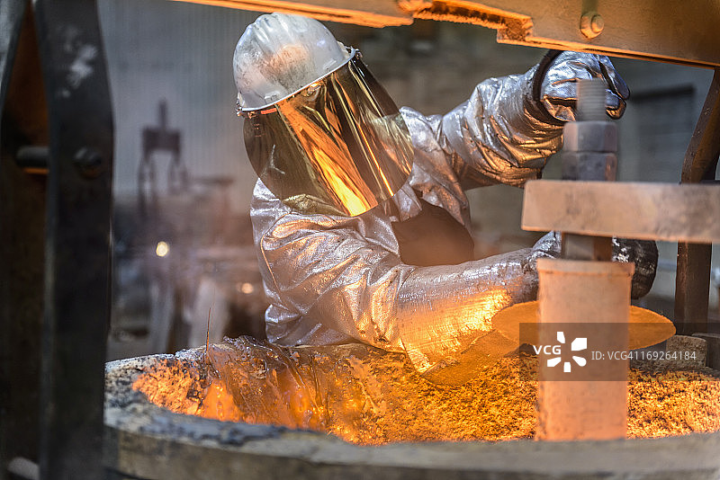 工人在铸造厂清洁熔融金属的烧瓶，正面图图片素材