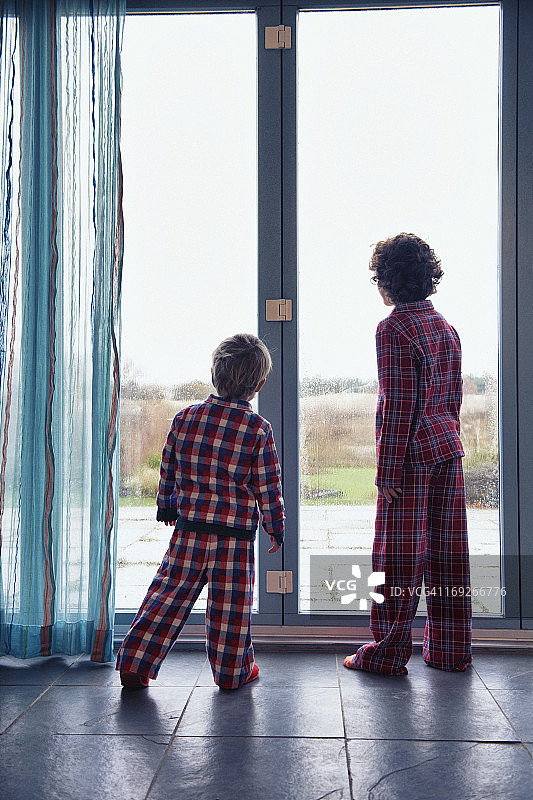 穿着睡衣看着窗外的男孩图片素材