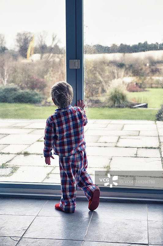 穿着睡衣向窗外看的男孩图片素材
