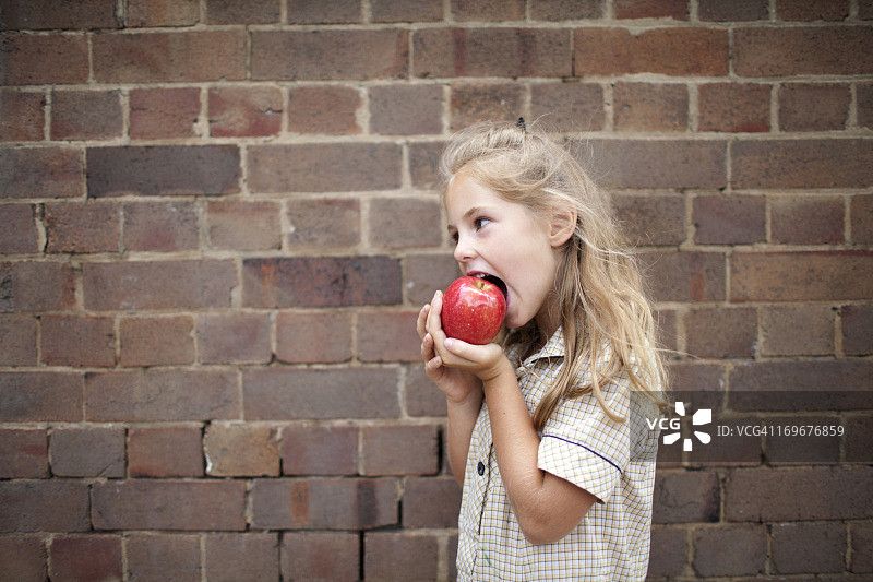 穿着校服吃苹果的年轻女孩图片素材