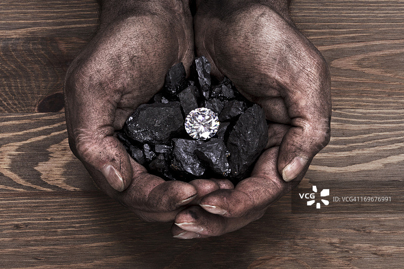 手中的煤炭和单颗钻石图片素材