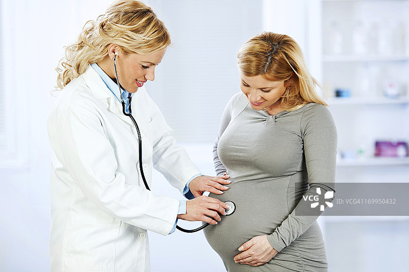 妇科医生用听诊器检查孕妇腹部图片素材