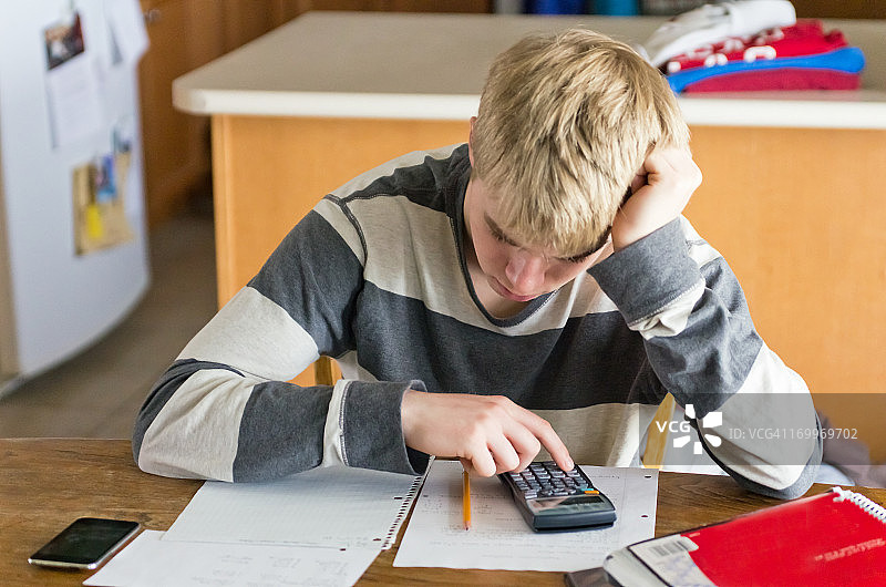 青少年男性在厨房餐桌上做作业图片素材