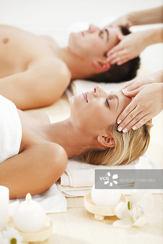 在水疗中心进行头部按摩的浪漫情侣。图片素材