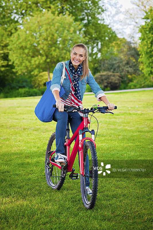 在公园里骑自行车的快乐年轻女人图片素材