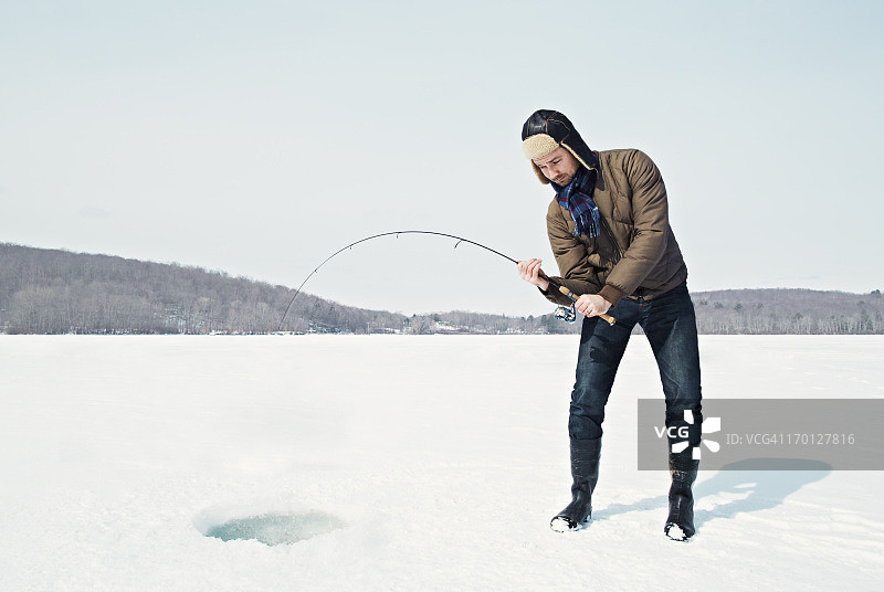 男子在冰冻的湖面上冰钓图片素材