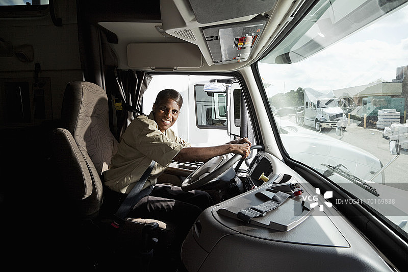 坐在半挂卡车驾驶室内的女卡车司机图片素材
