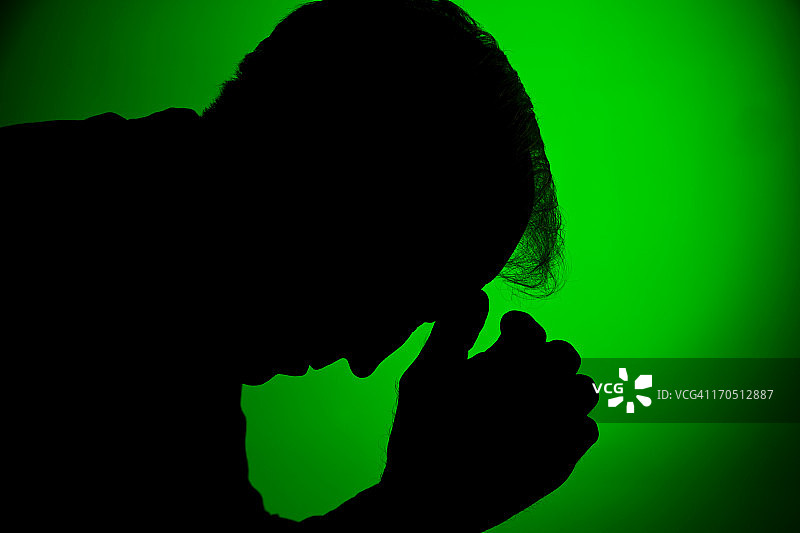 绿色背景下的沮丧男人剪影图片素材