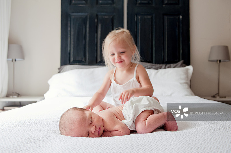 小女孩和新生婴儿在床上图片素材