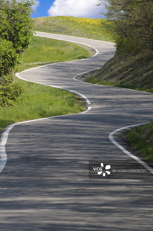从阴影蜿蜒进入阳光和光明未来的乡村公路图片素材
