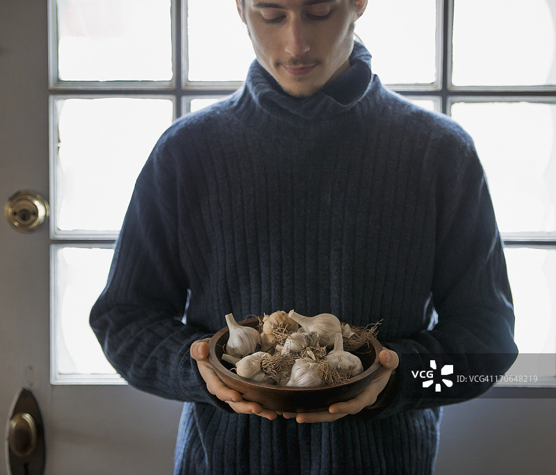 美国纽约州的冬季有机农场：一位年轻人拿着一束大蒜图片素材