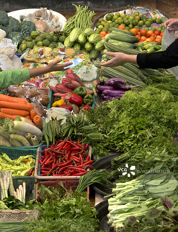 顾客购买蔬菜时的现金交易图片素材