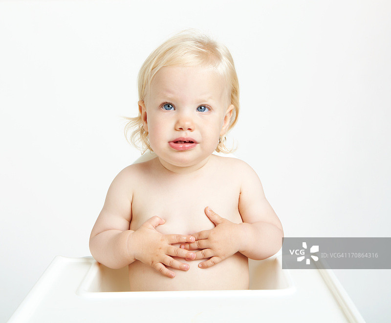 坐在高脚椅上，双手放在肚子上的婴儿图片素材