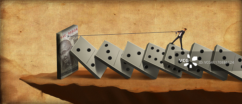 站在多米诺骨牌上为钱挣扎的商人图片素材