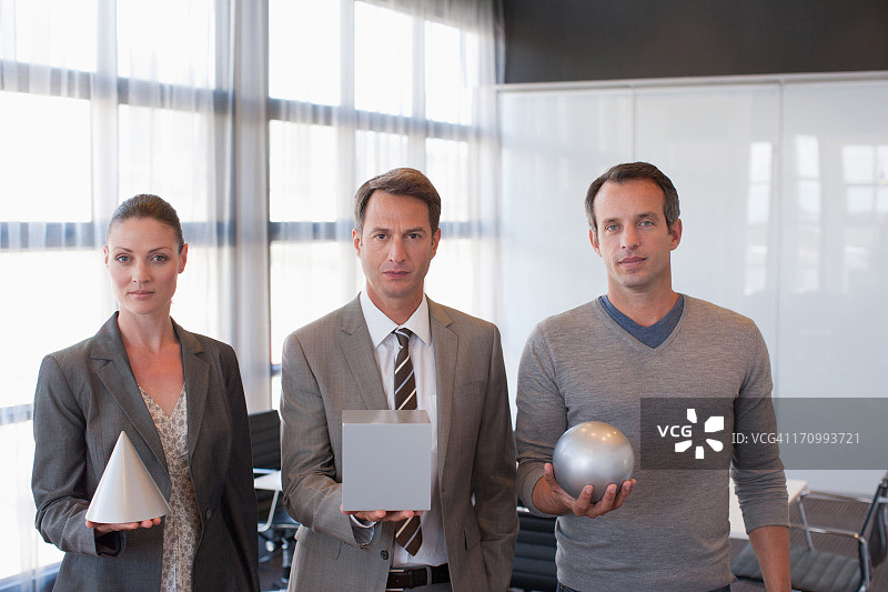 商务人士拿着球体、立方体和锥体图片素材