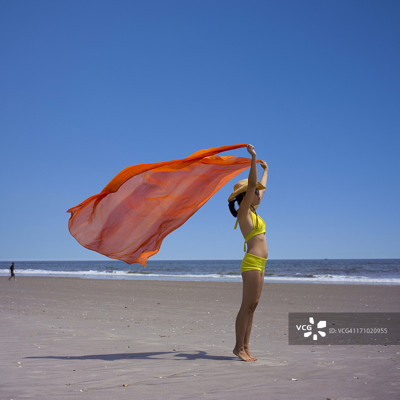 在海滩上手持红旗的女人肖像图片素材