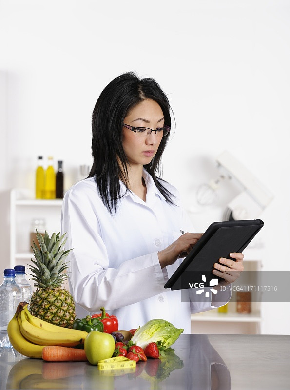 亚裔美国医护专业人员在数字平板电脑上查看内容图片素材