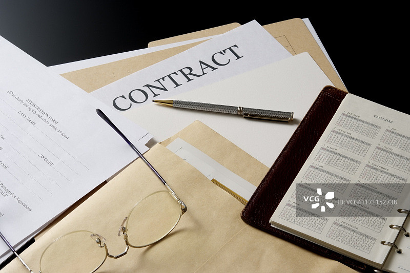 办公桌上的合同文件和个人记事本图片素材