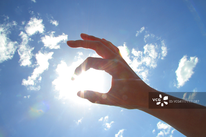 用手捏住天空中的太阳图片素材
