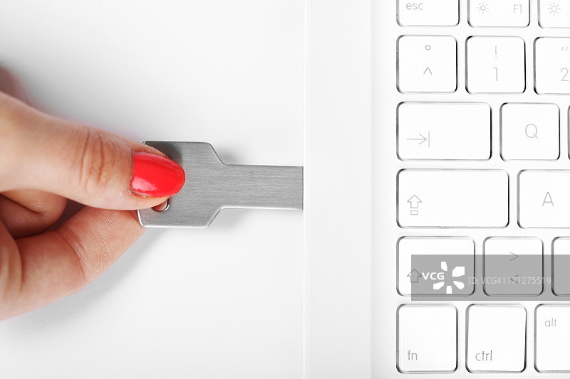 白色笔记本电脑上连接的USB闪存盘图片素材