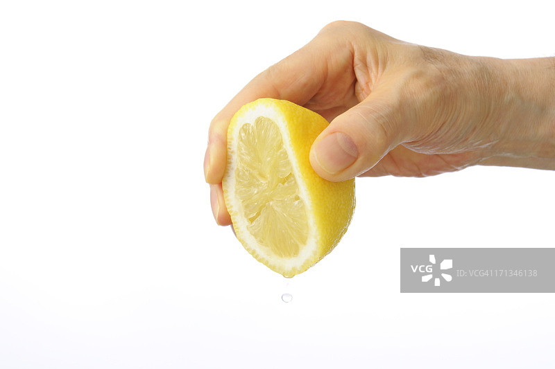 白色背景上手挤压柠檬的特写图片素材
