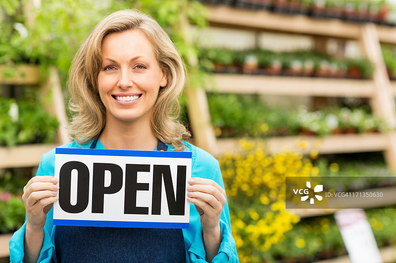 女园艺工 holding 一个开放 sign 板图片素材