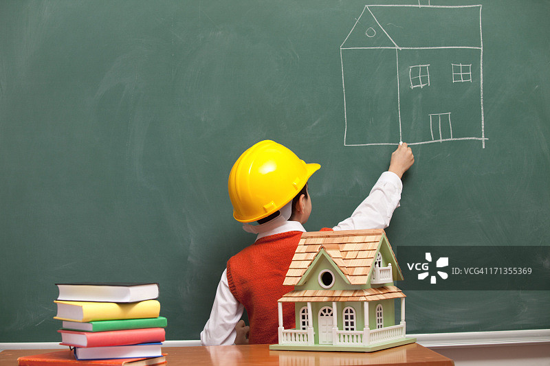 戴着头盔的小工程师在黑板上画房子图片素材