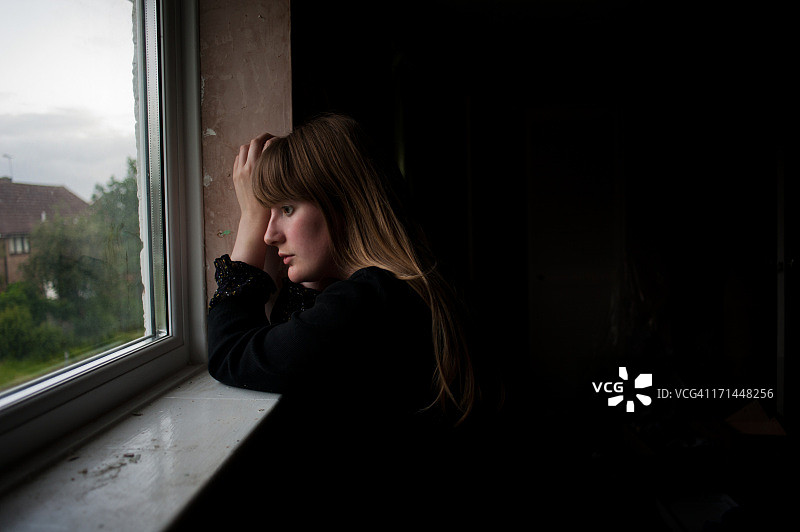 年轻金发女子在窗边等待图片素材