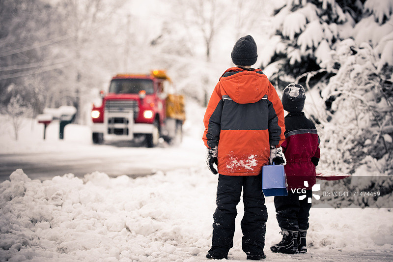 两个男孩观看扫雪机驶过图片素材