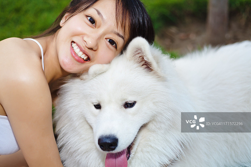 女孩在草地上与萨摩耶犬玩耍图片素材